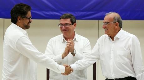 FARC's Ivan Marquez (L) and Colombia's Humberto de la Calle (R) shake hands over their historic peace deal Wednesday while Cuba's Foreign Minister Bruno Rodriguez looks on. © Alexandre Meneghini