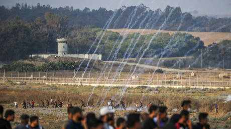 Palestinian protesters flee from tear gas fired by Israeli forces across the fence during clashes in the Gaza Strip on June 28, 2019. 