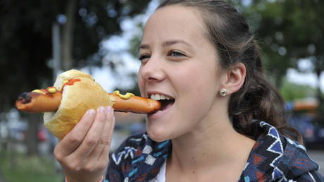 Young German enjoys traditional German sausage in a bun.