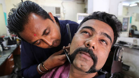 A man gets his moustache trimmed similar to the one sported by Indian Air Force pilot Abhinandan Varthaman in Ahmedabad, India.  © Reuters / Amit Dave