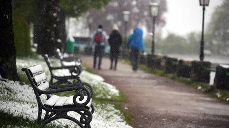 People walk past snow covered benches at the lake Schliersee, after snow fall in southern Germany, May 5, 2019. © REUTERS/Michael Dalder