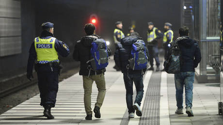FILE PHOTO A police officer escorts migrants from a train at Hyllie station outside Malmo, Sweden. ©  Reuters / Johan Nilsson