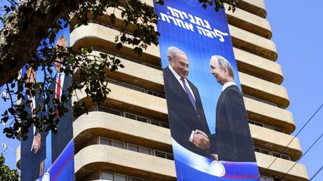 Election banner of Israeli Likud Party, showing Benjamin Netanyahu shaking hands with Vladimir Putin, with a caption in Hebrew: "Netanyahu, in another league." © AFP / Jack Guez
