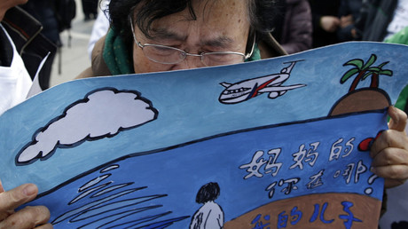 Wang Guohui, mother of a passenger of the missing Malaysia Airlines flight MH370, cries while holding a painting which her family made for wishing the return of her son, at Yonghegong Lama Temple in Beijing March 8, 2015. © Kim Kyung-Hoon