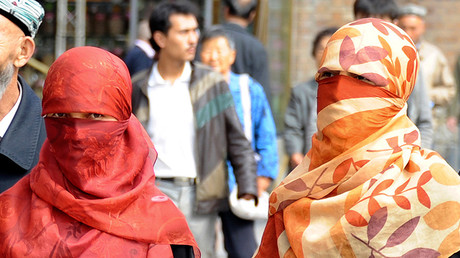 Uighur women wearing face veils walk on a street in Urumqi © Stringer