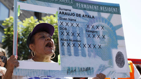 FILE PHOTO. A woman holds a replica green card sign during a protest. ©REUTERS / Lucy Nicholson
