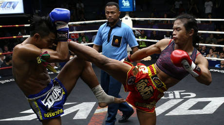Trans-woman Muay Thai boxer Nong Rose Baan Charoensuk (R) kicks a male opponent in Bangkok, Thailand, July 13, 2017