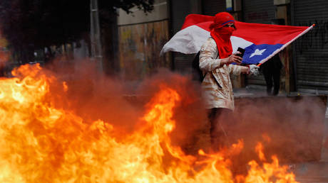 A protester walks past a burning barricade in Concepcion, Chile © Reuters / Jose Luis Saavedra