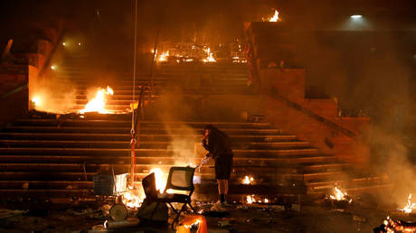 An anti-government protester sets fire to the entrance to Hong Kong Polytechnic University (PolyU) to stop police in Hong Kong, China, November 18, 2019.