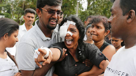 Kumari Fernando, who lost her husband and two children during the bombing at St Sebastian's Church yells towards the graves during a mass burial for victims of Colombo bombings. File photo.