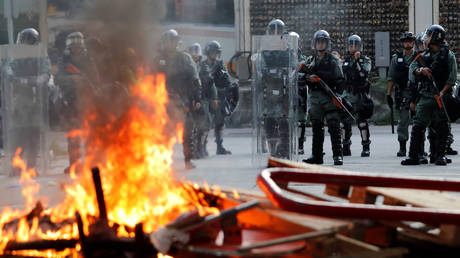 Riot police stand guard behind a burning barricade as they disperse anti-government protesters after a march in Tuen Mun, Hong Kong, China September 21, 2019.  ©  REUTERS/Tyrone Siu