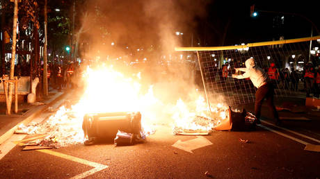 A Catalan pro-independence demonstrator throws a fence into a fire during a protest against police action in Barcelona, Spain, October 26, 2019. © REUTERS/Sergio Perez