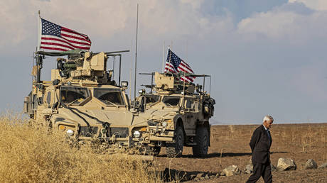 A Syrian man walks on as US armoured vehicles patrol the northeastern town of Qahtaniyah at the border with Turkey, on October 31, 2019.
