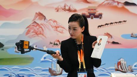 FILE PHOTO A journalist uses her mobile phone to broadcast live in Beijing on April 25, 2019. © AFP / Wang Zhao