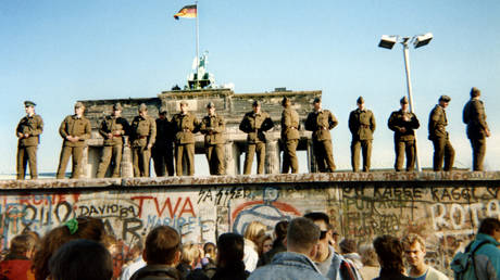 East German border guards stand on a section of the Berlin Wall on November 11, 1989. © Gunther Kern / AFP