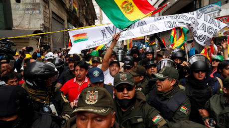 Police officers escort Luis Fernando Camacho, a Santa Cruz civic leader and major opposition figure, as he waves a national flag during a protest against Bolivia's President Evo Morales in La Paz, Bolivia November 10, 2019. © REUTERS/Carlos Garcia Rawlins