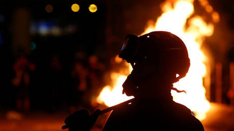 A protester is seen in front of a fire in the Mong Kok area in Hong Kong, China November 11, 2019. © REUTERS/Thomas Peter
