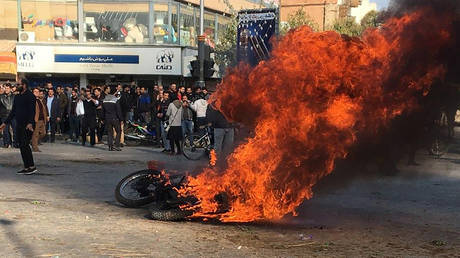 Iranian protesters gather around a burning motorcycle during a demonstration against an increase in gasoline prices. ©AFP