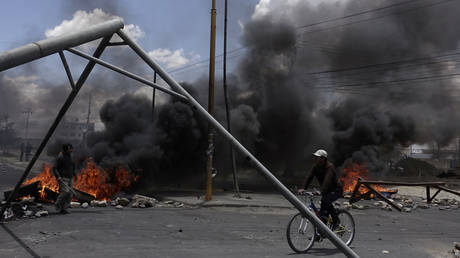 A cyclist rides next to a blocked petrol plant of Senkata in the outskirts of La Paz, Bolivia, November 19, 2019.