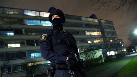 A policeman looks on after an object exploded next to a police station in Rosengard, Malmo