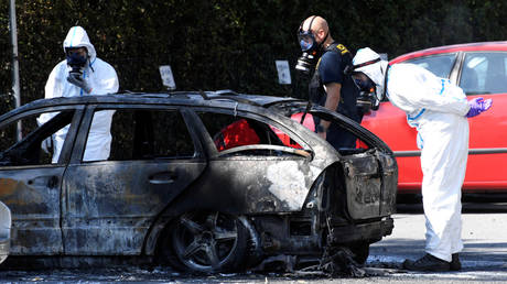 Police and criminal technical investigators look at a burnt car near the area of a shooting in Ribersborg, August 2019 © Reuters / Johan NIlsson