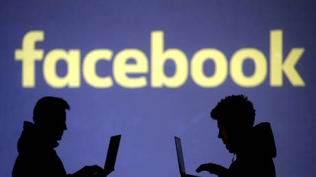 Silhouettes of laptop users are seen next to a screen projection of Facebook logo in this picture illustration taken March 28, 2018. © REUTERS/Dado Ruvic