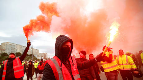 Protesters hold up flares as French Labour unions members demonstrate against French government's pensions reform plans in Marseille as part of a day of national strike and protests in France, December 5, 2019.