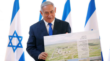 FILE PHOTO: Benjamin Netanyahu poses with a placard given while visiting a Jordan Valley settlement © REUTERS/Amir Cohen