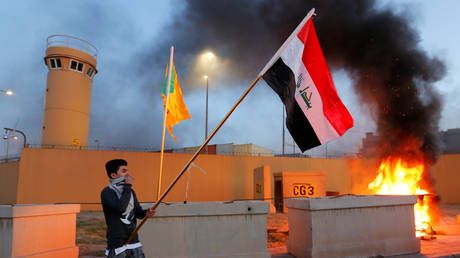 A protester holds an Iraqi flag outside the main gate of the US Embassy in Baghdad, Iraq December 31, 2019.