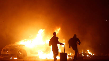 People run while a vehicle burns during riots at Hal Far Open Centre migrant camp in Hal Far, Malta, October 21, 2019