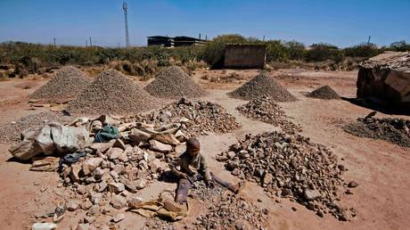 A child breaks rocks extracted from a cobalt mining at a copper mine quarry and cobalt pit in Lubumbashi, Congo