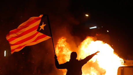 A protester waves a Catalan pro-independence flag next to burning garbage bins during a chaotic demonstration in Barcelona, Spain, December 18, 2019.