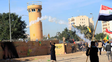 Protesters and militia fighters throw back a tear gas canister used by U.S. Embassy security men during a protest to condemn air strikes on bases belonging to Hashd al-Shaabi (paramilitary forces), outside the embassy in Baghdad, Iraq January 1, 2020.