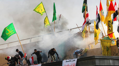 Potesters and militiamen run from tear gas fired by security at the US embassy in Baghdad © Reuters / Thaier al-Sudani
