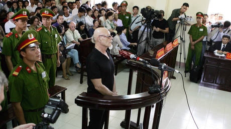 A policeman watches former British rock star Gary Glitter standing trial in a Vietnamese court, on charges of child sex abuse © AFP / HOANG DINH NAM