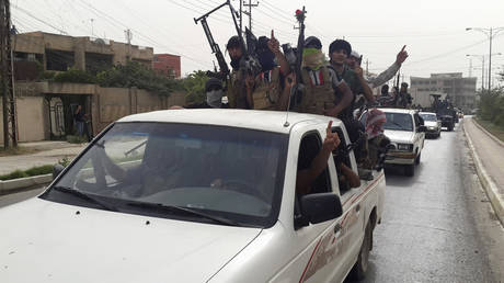 FILE PHOTO: IS terrorist fighters celebrate on vehicles plundered from Iraqi security forces in Mosul, June 12, 2014