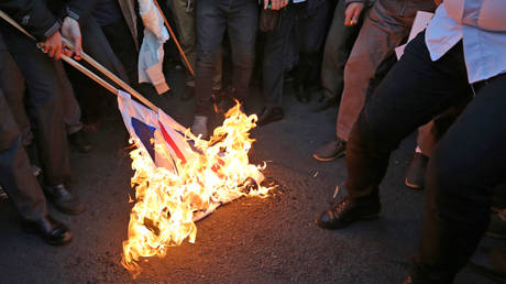 Iranian demonstrators set alight a Union Jack in front of the British embassy in  Tehran on January 12, 2020.