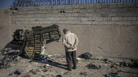 A man stands near a piece of debris of a Boeing 737 Ukrainian passenger plane at the air crash site in Parand district, southern Tehran, Iran, on Jan. 8, 2020. © Global Look Press/Xinhua/Ahmad Halabisaz
