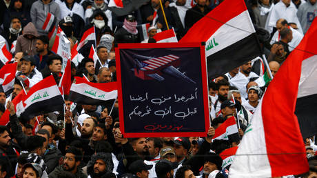 Supporters of Iraqi Shi'ite cleric Moqtada al-Sadr hold a sign reading "Get out of our land before you leave defeated" © REUTERS/Alaa al-Marjani