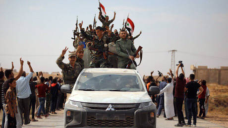 Locals greet Syrian army soldiers in the town of Ain Issa, Syria.