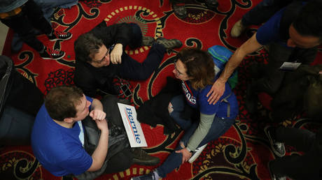 Attendees sit on the floor after the results of the US Democratic Party’s caucus were delayed on February 3, 2020 in Des Moines, Iowa. © AFP / Getty Images / Joe Raedle