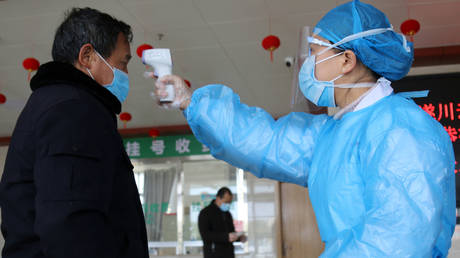 FILE PHOTO: A medical worker takes the body temperature of a man at an entrance to a hospital in Suichuan, China as the country is hit by an outbreak of the new coronavirus.