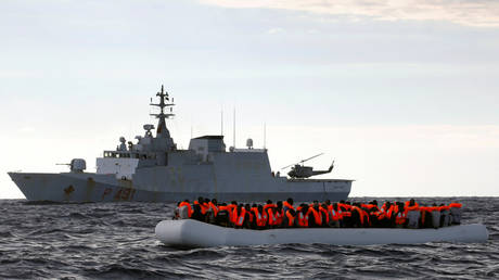 FILE PHOTO: An overcrowded raft carrying African migrants is seen in front of an Italian Navy vessel in 2017 © REUTERS/Yannis Behrakis