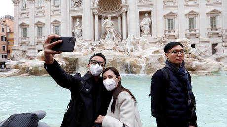 Tourists wearing protective masks take a selfie in front of ther Trevi's Fountain in Rome