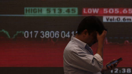 FILE PHOTO: A man stands in front of a screen displaying news of market updates inside the Bombay Stock Exchange (BSE) building in Mumbai, India.