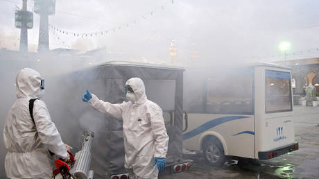 Members of the medical team spray disinfectant in Mashhad, Iran