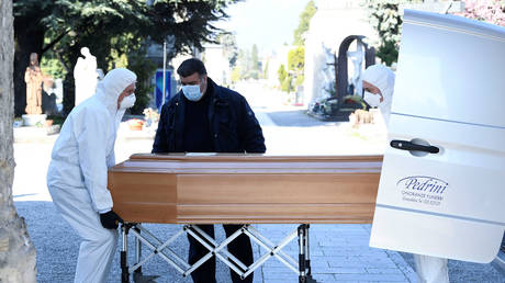 Men in protective masks transport a coffin of a person who died from Covid-19, into a cemetery in Bergamo, Italy March 16, 2020. © Reuters / Flavio Lo Scalzo