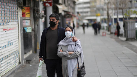 A couple wear protective face masks as they walk in Tehran, Iran on March 26, 2020 © WANA (West Asia News Agency)/Ali Khara via REUTERS