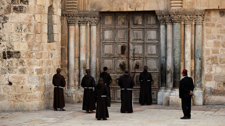 Monks pray in front of the locked door of Jerusalem's Church of the Holy Sepulchre. © REUTERS/ Ammar Awad