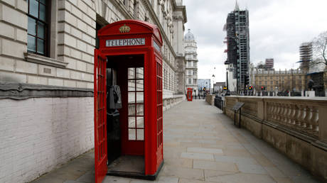 The door of a red London telephone box hangs open on a empty street near the Houses of Parliament in London on April 2, 2020 © AFP / Tolga Akmen